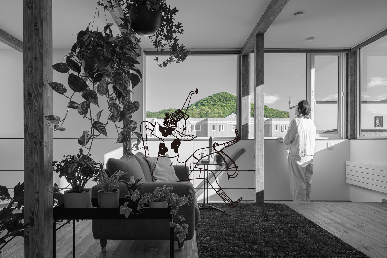 店舗付き住宅のアートホーム施工事例。2階リビングから山を眺める女性。